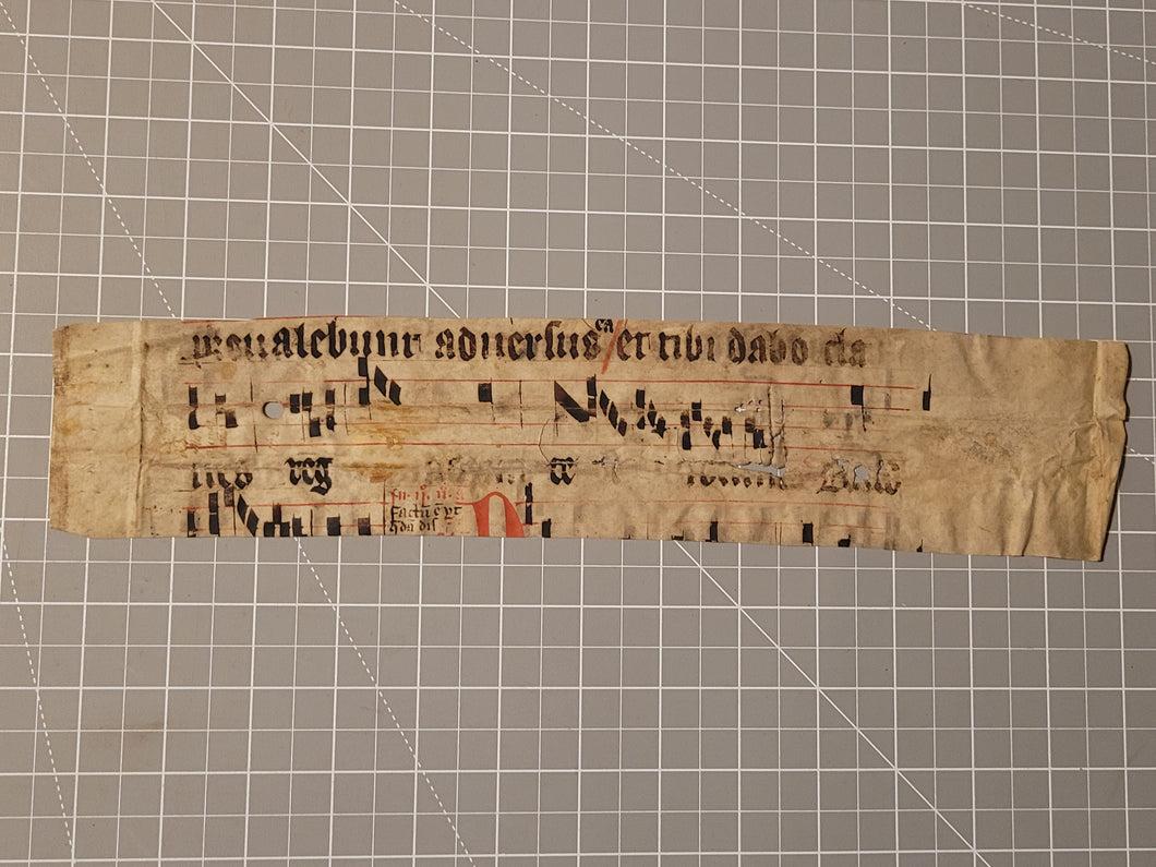 Leaf Fragment from a Latin Missal, Germany, 15th Century. Manuscript on Parchment.  Two Lines of Gothic Script and Musical Notation. Recovered from a Binding